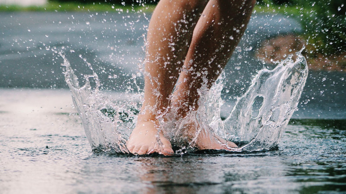 Bare feet splashing through shallow water outdoors, illustrating an article on nail fungus home remedies