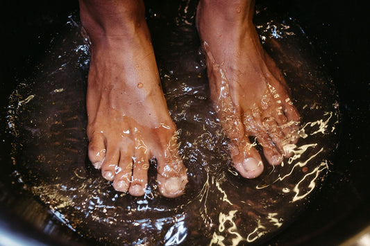 Feet soaking in a bowl of water, the at home aftercare routine that follows a debridement appointment