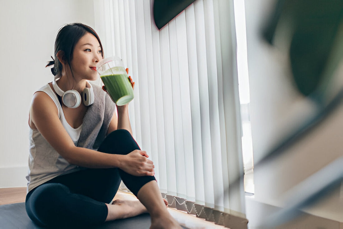 Woman in workout clothes sitting barefoot by a window drinking a green smoothie after exercise, the everyday nutrition side of iodine intake