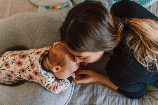 Overhead view of a mother leaning nose to nose with her infant in a floral sleepsuit, the early years maternal iodine intake affects
