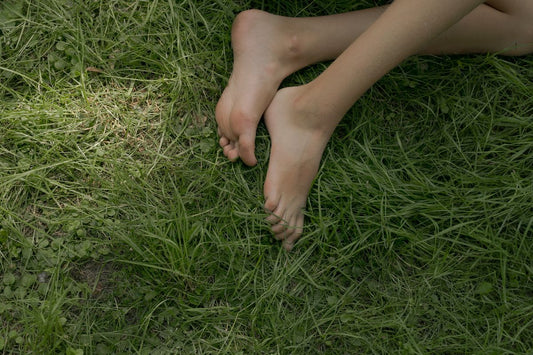 Bare feet resting on grass, the clear-looking nails an iodine routine works toward