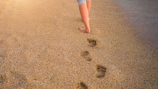 Barefoot walking on sand leaving footprints