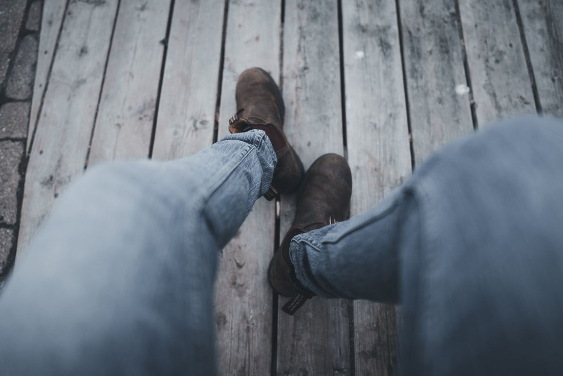 Worker in jeans and heavy work boots seated with feet up, resting after a shift