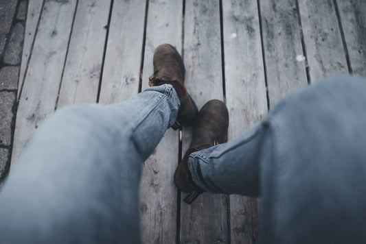 Worker in jeans and heavy work boots seated with feet up, resting after a shift