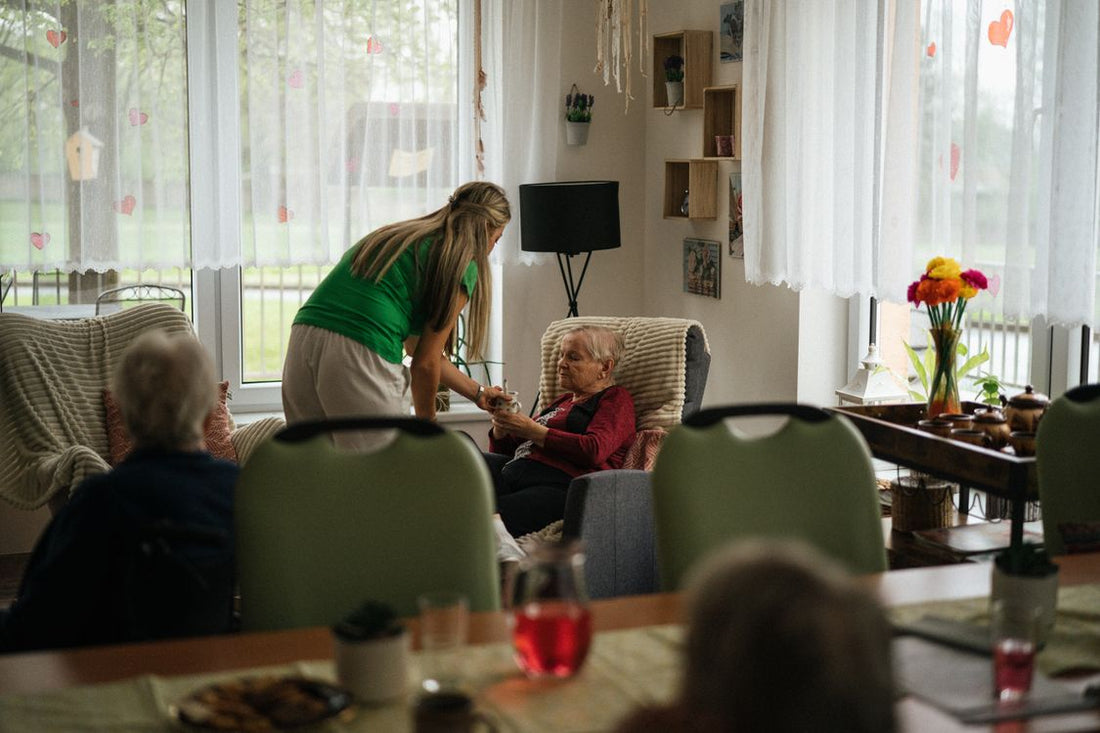 Caregiver gently assisting an elderly woman in a warm, home-like care setting