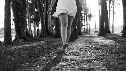 Person walking barefoot along a sunlit forest path