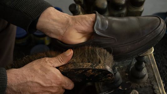 A shoe being cleaned by hand with a brush