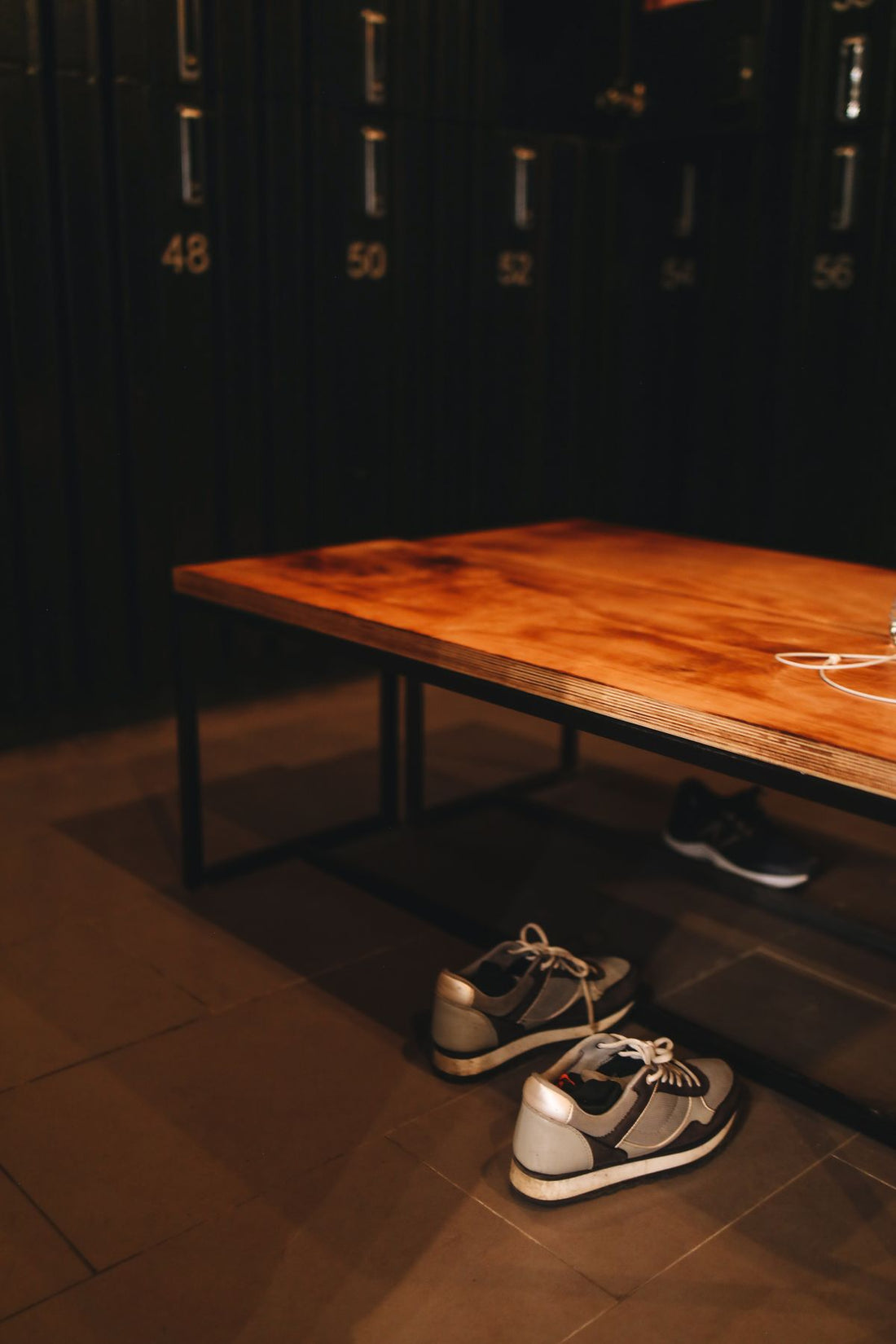 Trainers under a bench in a gym locker room, the footwear step the Lume on feet hack skips