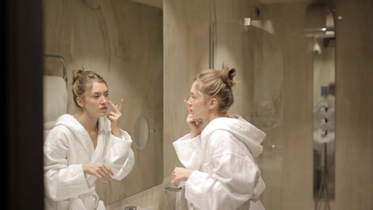 Person applying moisturiser at a bathroom mirror