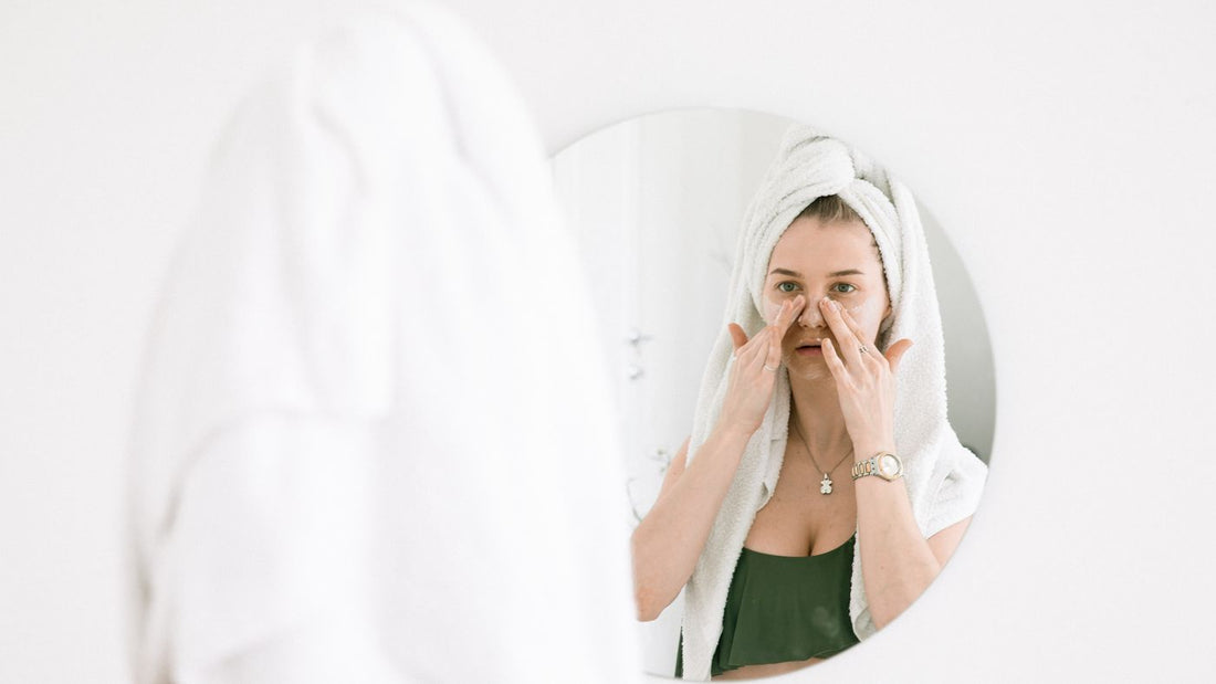 Person following a skincare routine at a bathroom mirror