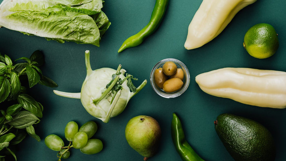 Flat lay of fresh vegetables and fruit on a green background