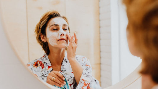 Person applying a face mask in front of a mirror