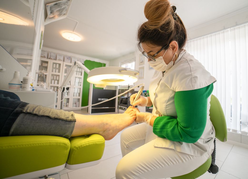 Foot-care specialist performing a nail procedure on a patient's toe in a clinic
