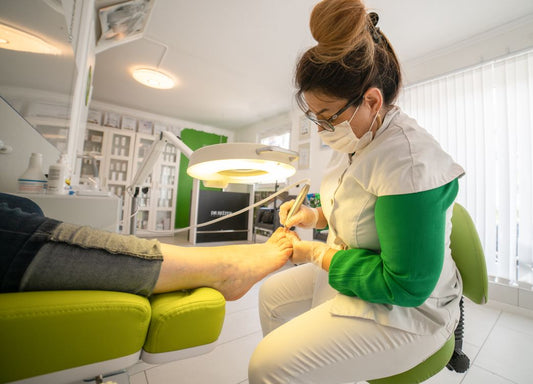 Foot-care specialist performing a nail procedure on a patient's toe in a clinic