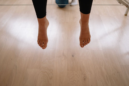 Bare feet above a wood floor after shoes come off, the moment foot odor is most noticeable