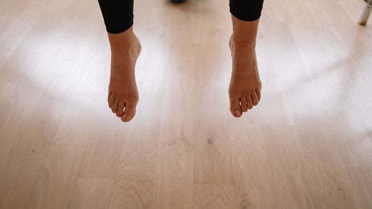 Bare feet resting above a wooden floor indoors