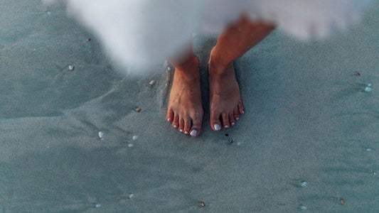 Bare feet on sand near the ocean
