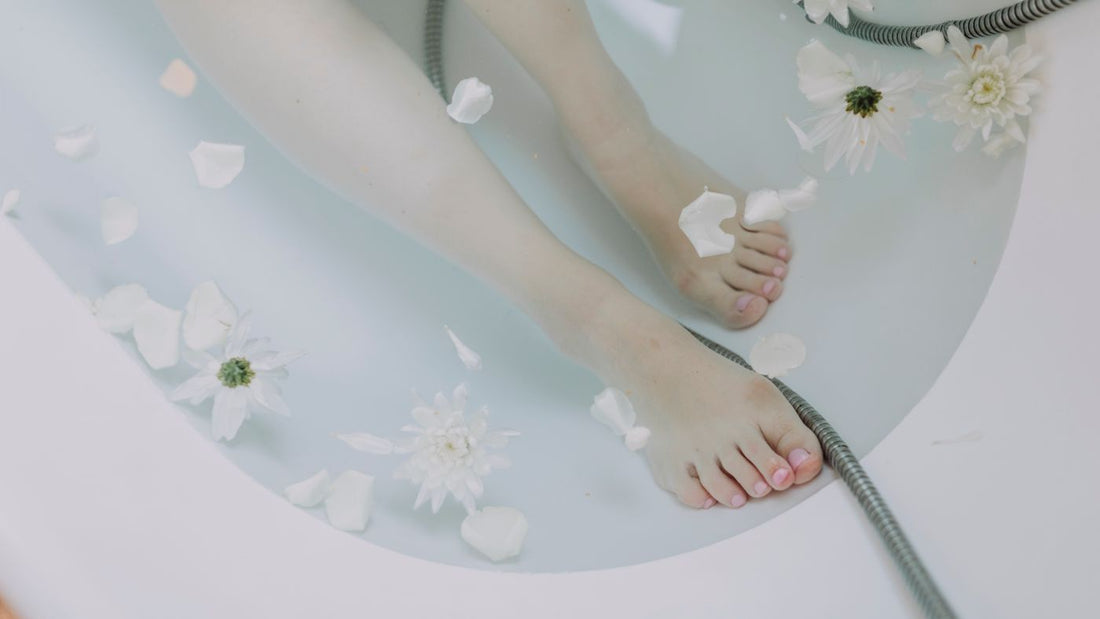 Feet resting in a warm foot bath with petals