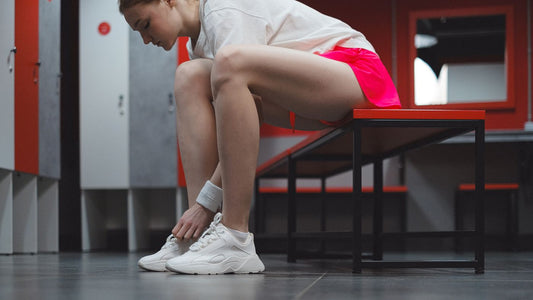 Person in sportswear tying their shoes in a locker room