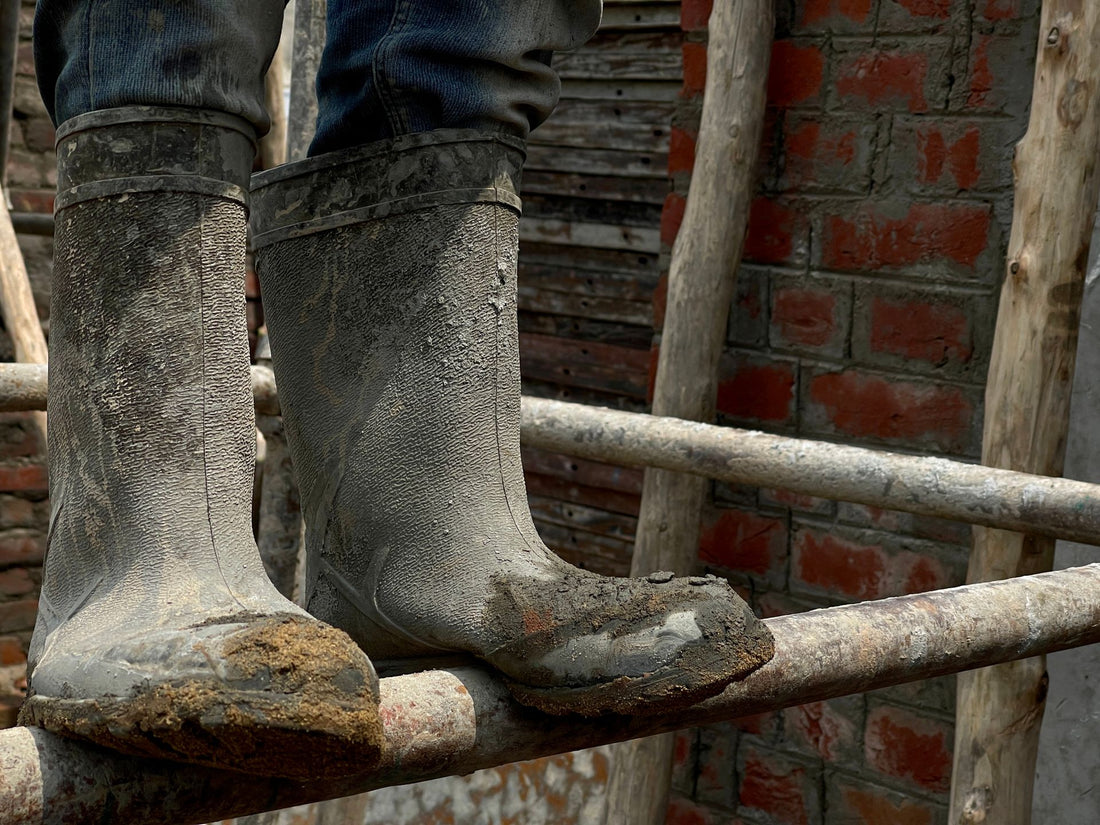 Muddy work boots worn through a full shift, the kind of enclosed footwear where shoe odor builds up