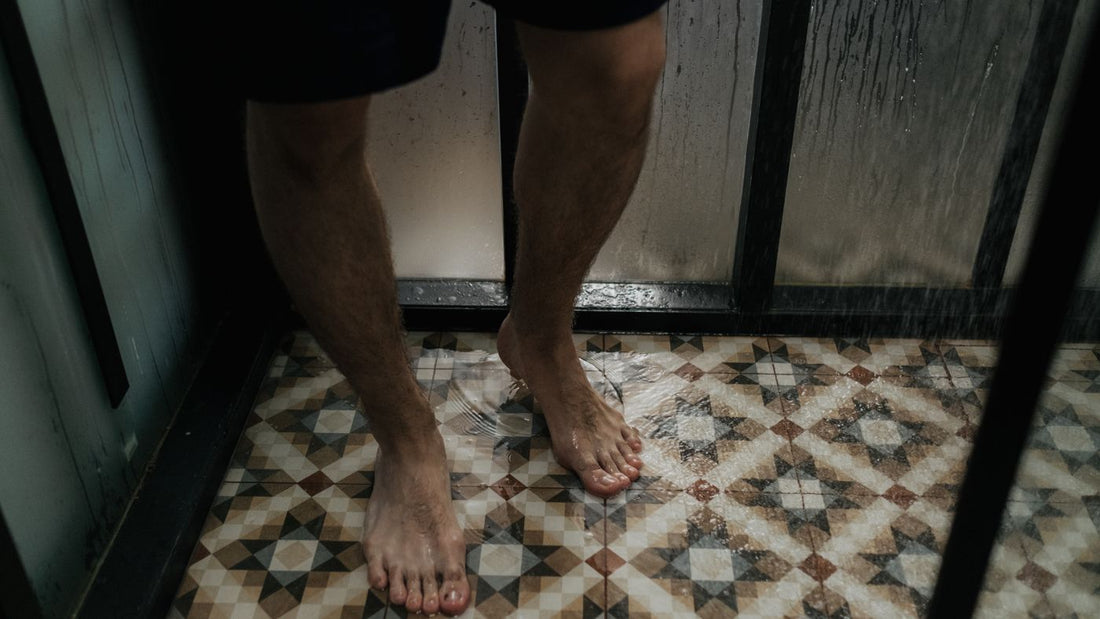 Bare feet standing on a wet tiled shower floor
