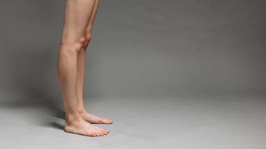 Bare feet and lower legs against a plain grey background