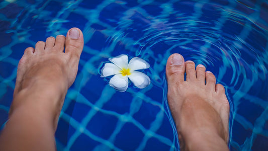 Bare feet at the edge of a clear blue pool