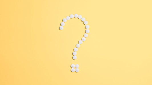 White pills arranged in the shape of a question mark, illustrating a comparison of Jublia and IodinePure for toenail fungus
