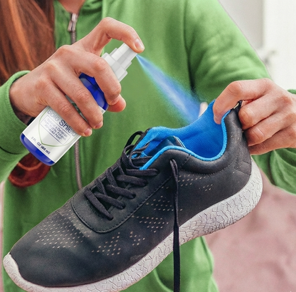 Person applying a spray to a black sneaker with blue interior