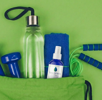 Green bag with water bottle, towel, weights, and jump rope on a green background