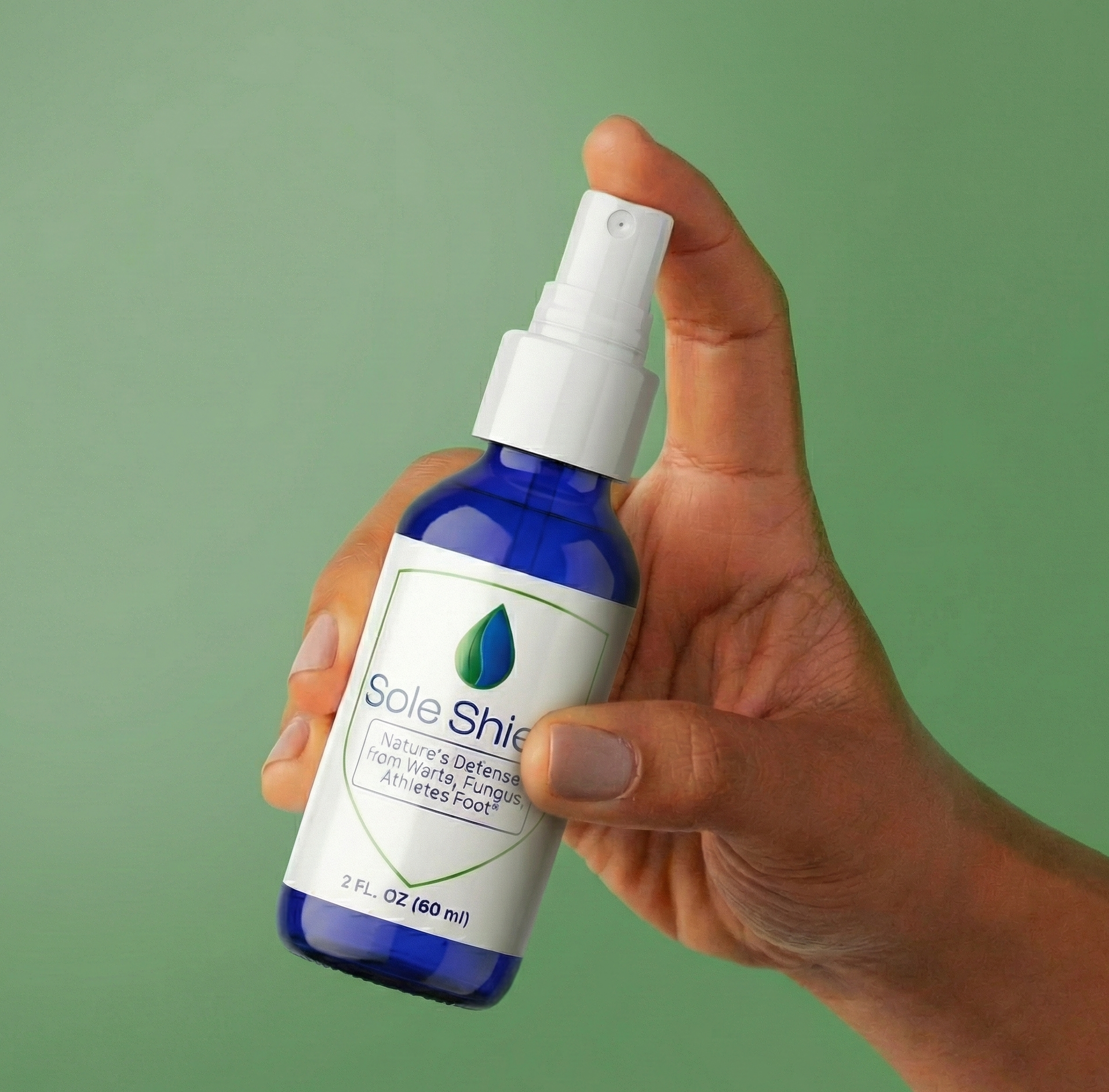 Hand holding a bottle of SoleShield against a green background
